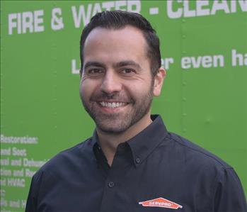 Male SERVPRO employee smiling in front of a green van.