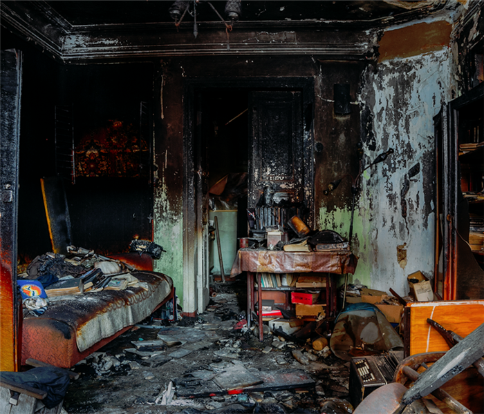 a fire damaged bedroom with debris and soot everywhere